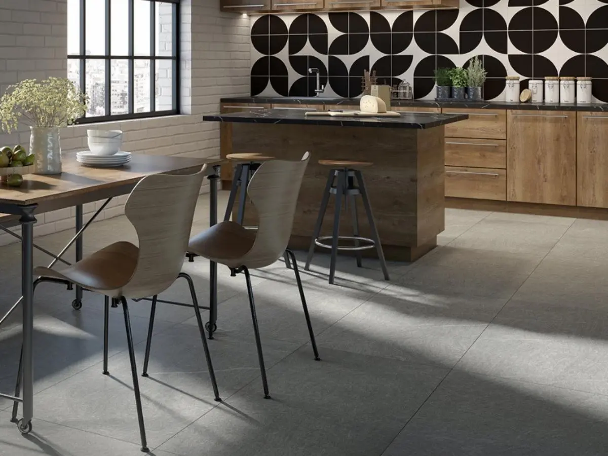 Cocina moderna con piso de losetas grises grandes y un llamativo salpicadero geométrico en blanco y negro